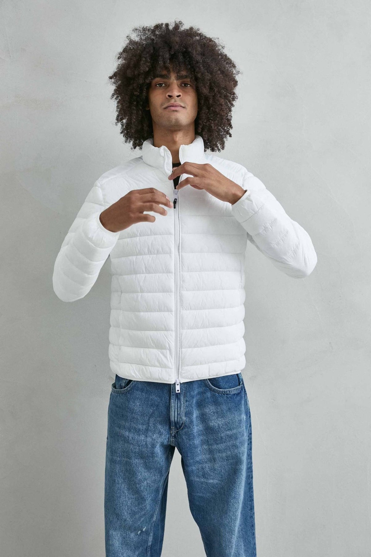 Chaqueta acolchada de hombre blanco con cuello alto y cremallera de doble cursor, vista frontal.
