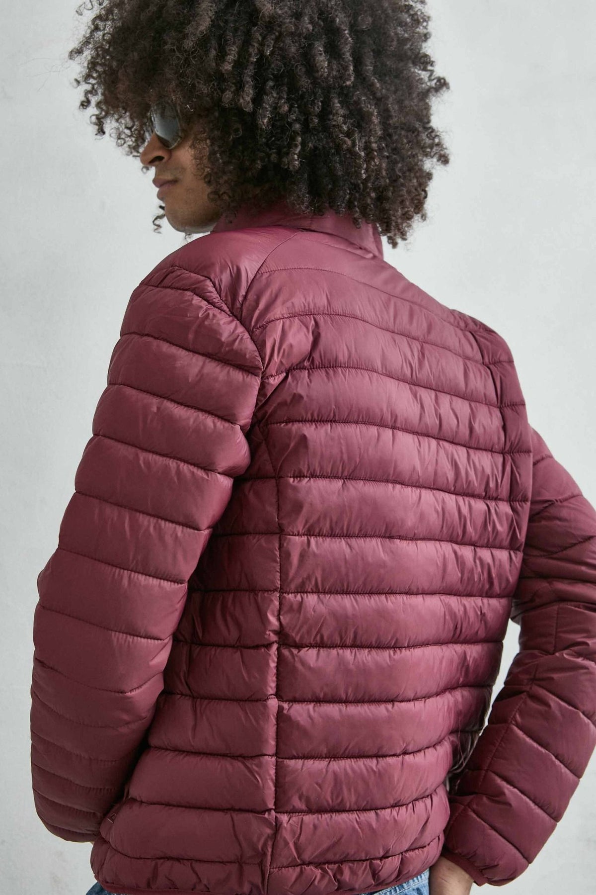 Chaqueta acolchada de hombre burdeos con cuello alto y cremallera de doble cursor, vista detalle.