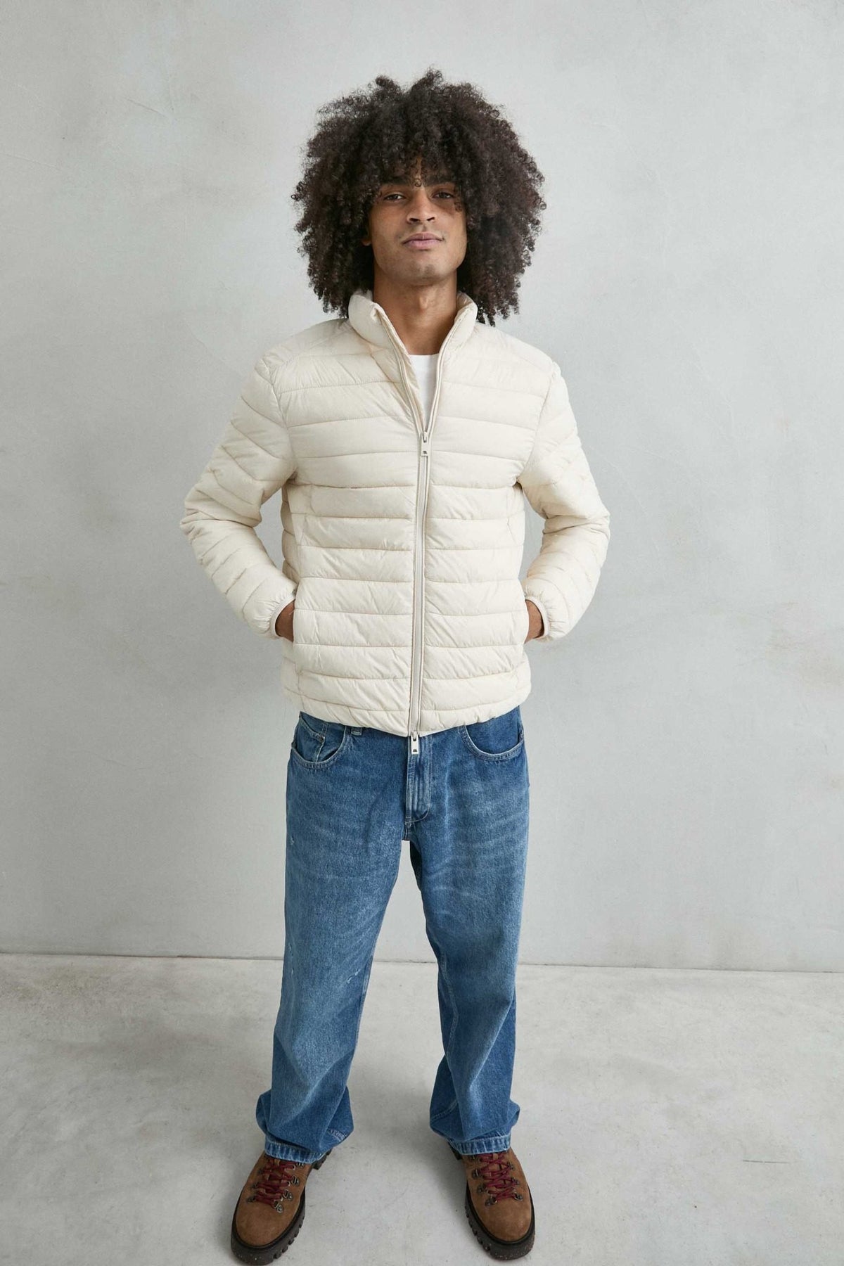 Chaqueta acolchada de hombre crema con cuello alto y cremallera de doble cursor, vista frontal.