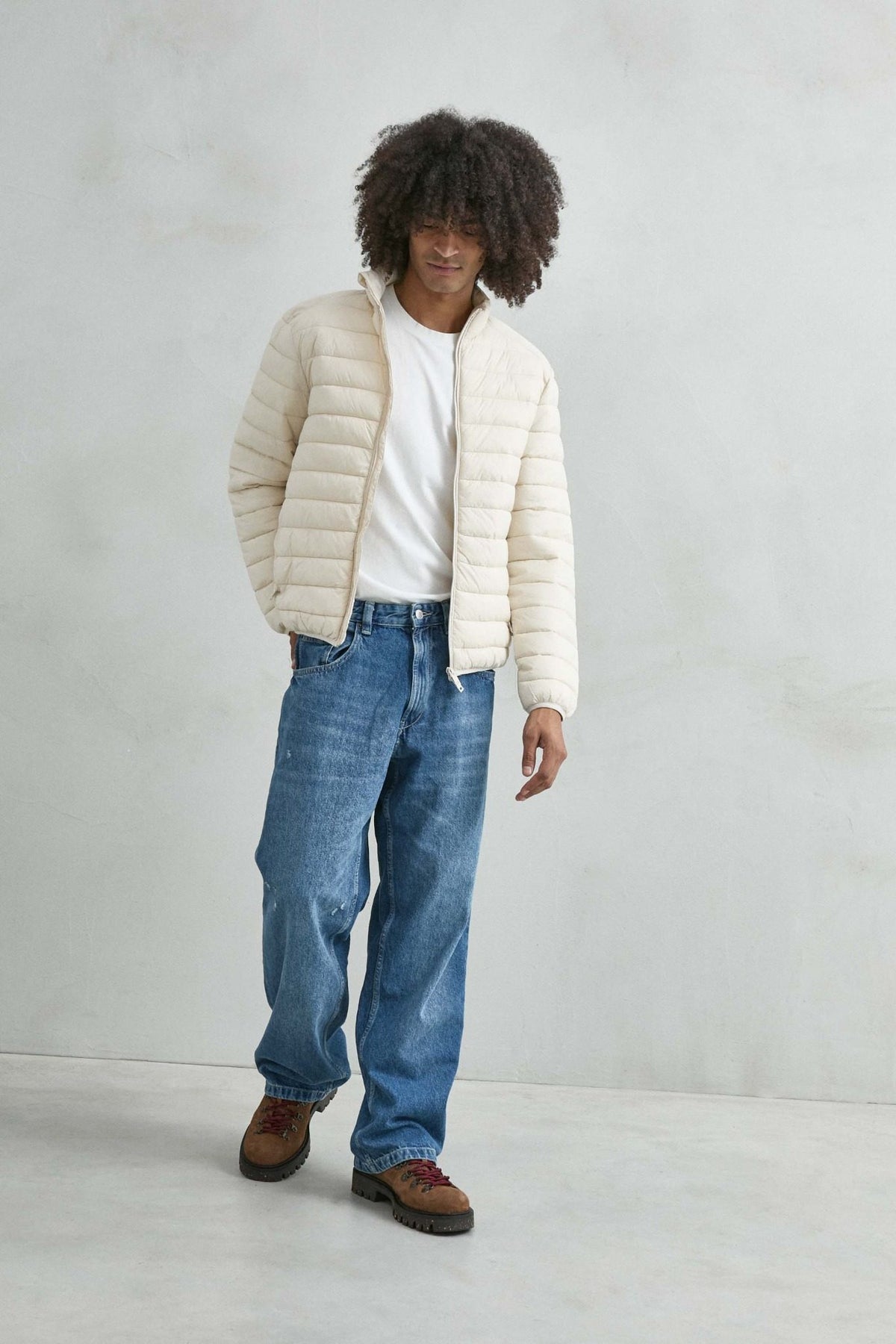 Chaqueta acolchada de hombre crema con cuello alto y cremallera de doble cursor, vista de cuerpo entero.