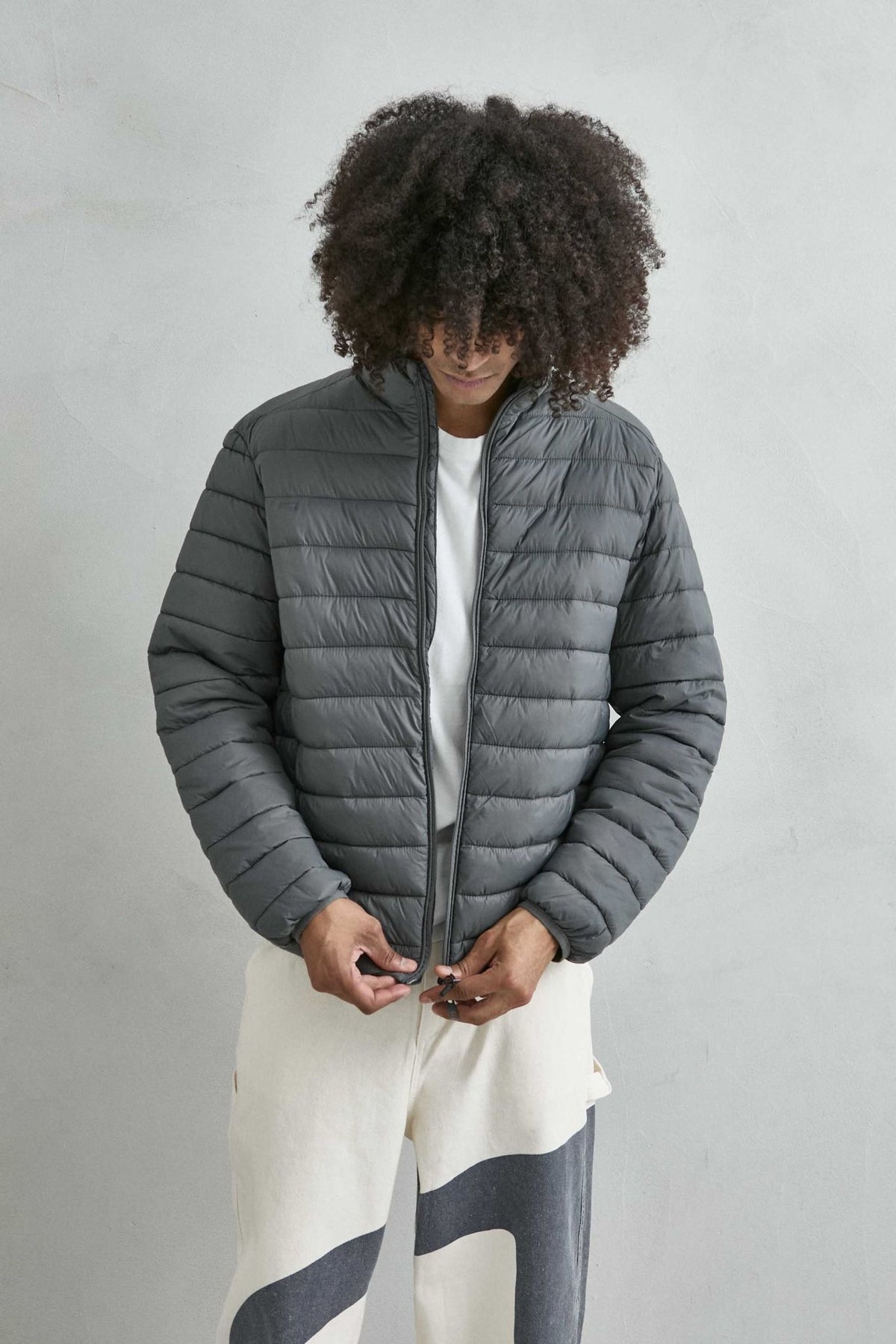 Chaqueta acolchada de hombre gris con cuello alto y cremallera de doble cursor, vista detalle.