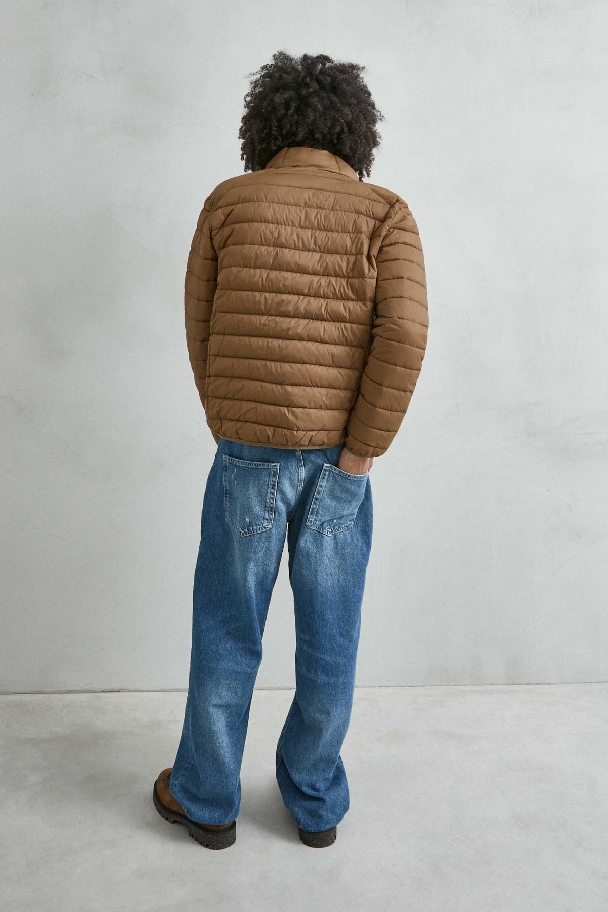 Chaqueta acolchada de hombre marrón con cuello alto y cremallera de doble cursor, vista espalda.
