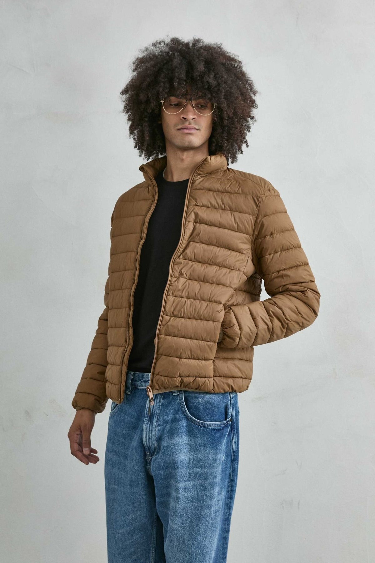 Chaqueta acolchada de hombre marrón con cuello alto y cremallera de doble cursor, vista frontal.