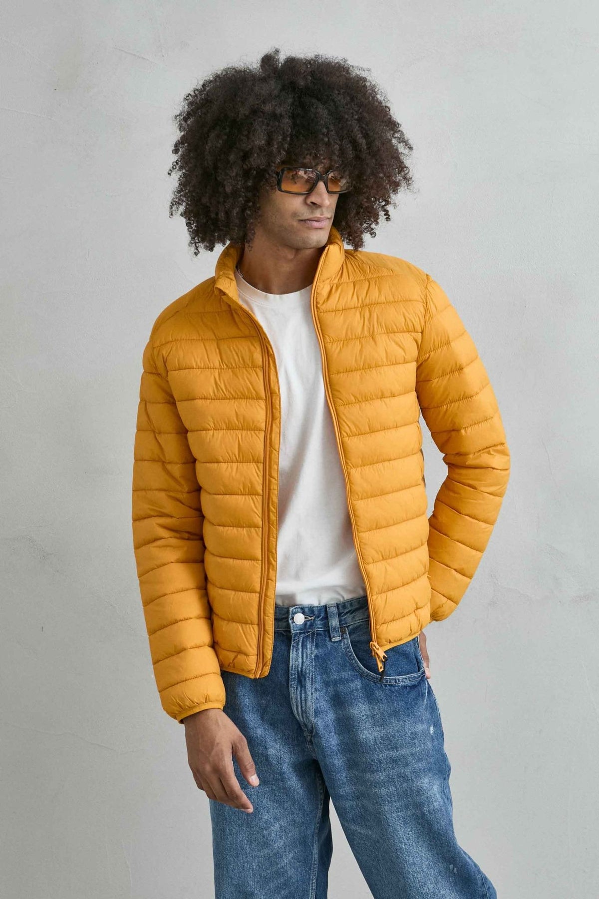 Chaqueta acolchada de hombre mostaza con cuello alto y cremallera de doble cursor, vista frontal.