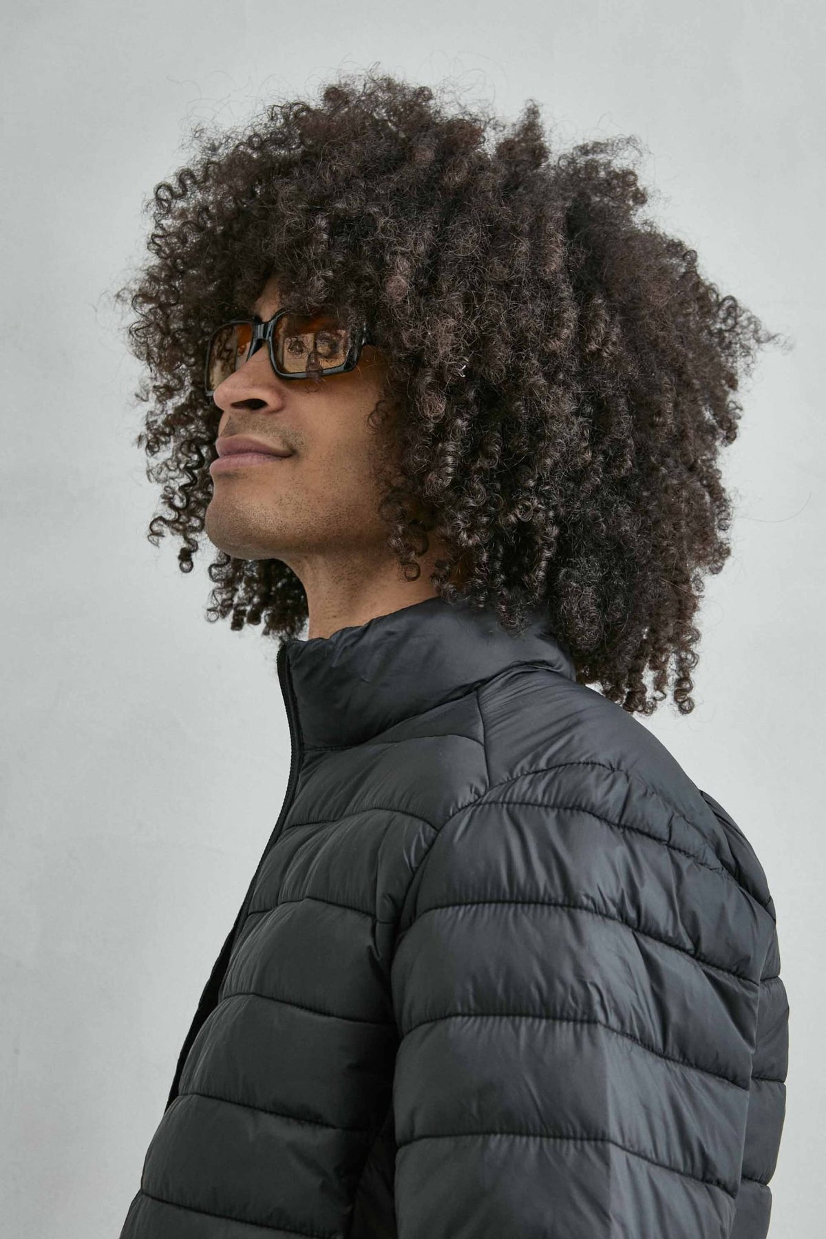 Chaqueta acolchada de hombre negro con cuello alto y cremallera de doble cursor, vista detalle.