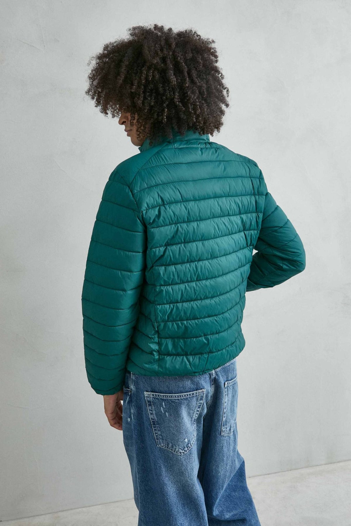 Chaqueta acolchada de hombre verde oscuro con cuello alto y cremallera de doble cursor, vista espalda.