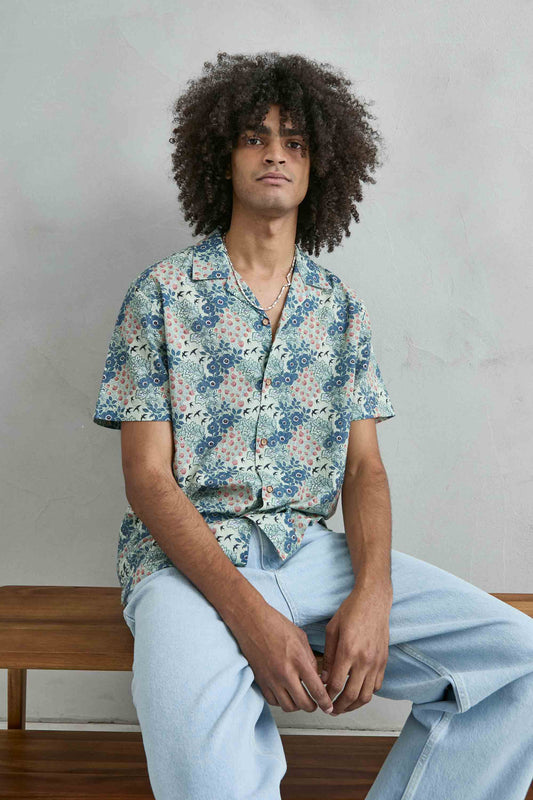 Detalle del estampado azul con flores hojas y aves en camisa hawaiana