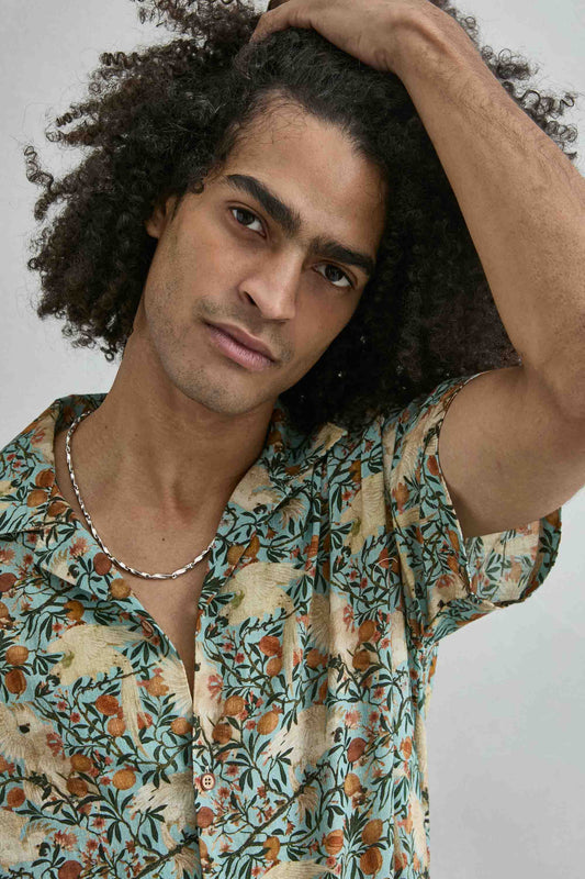 Detalle del estampado tropical con loro hojas y frutas en camisa hawaiana