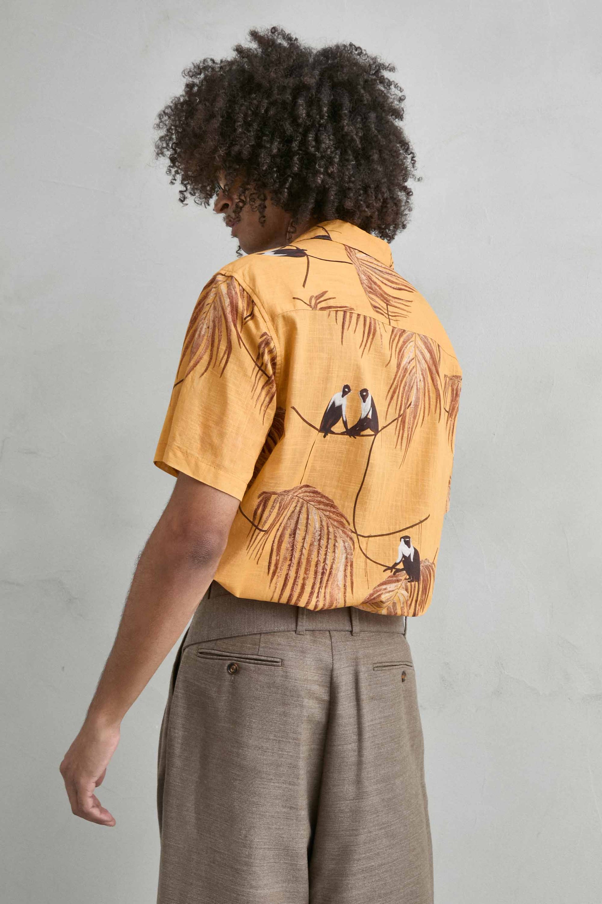 Detalle del mono de cola larga en estampado tropical sobre fondo amarillo