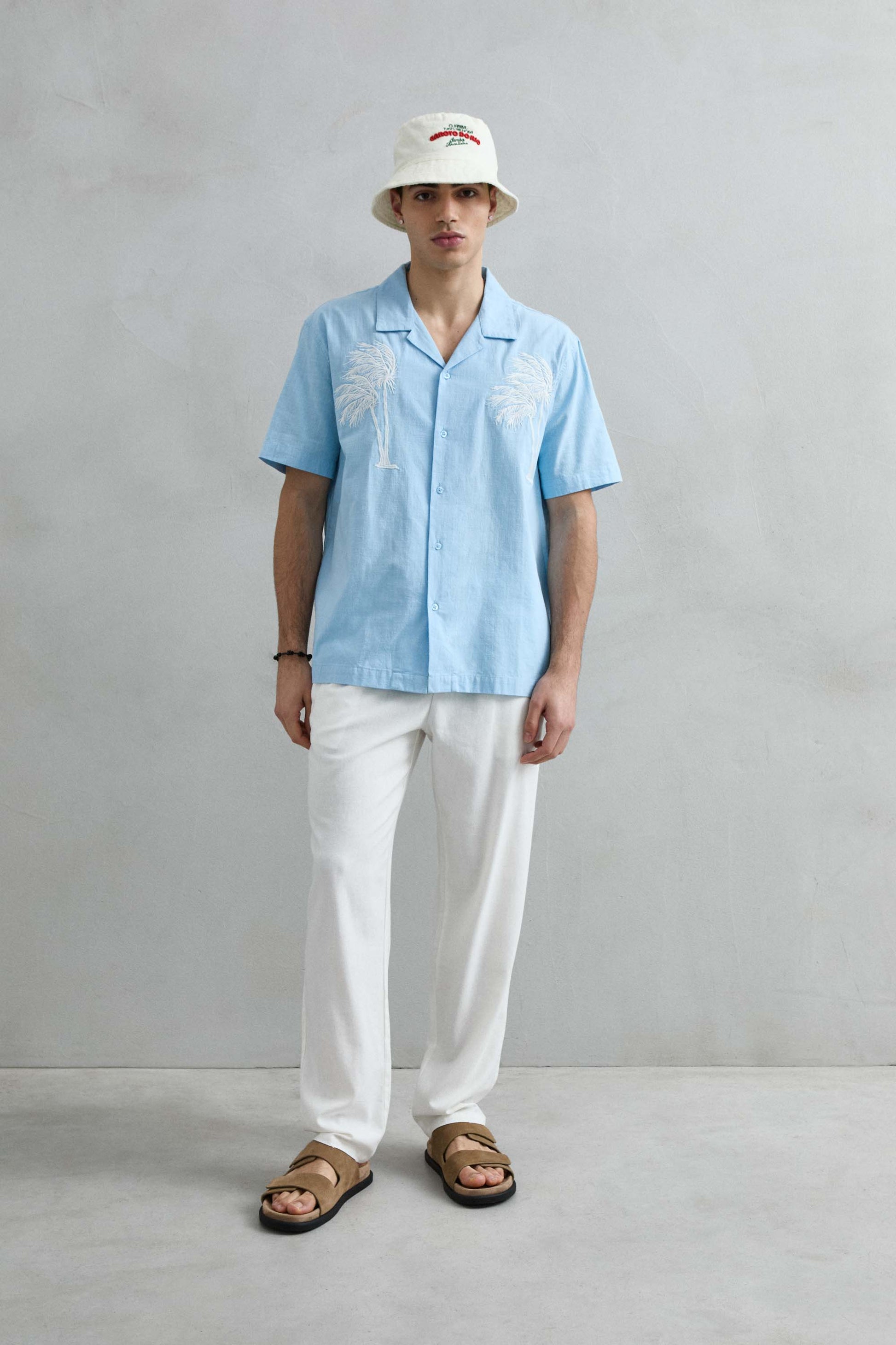 Modelo luciendo camisa de manga corta azul claro de Imperio con detalle de cuello cubano y ajuste relajado.