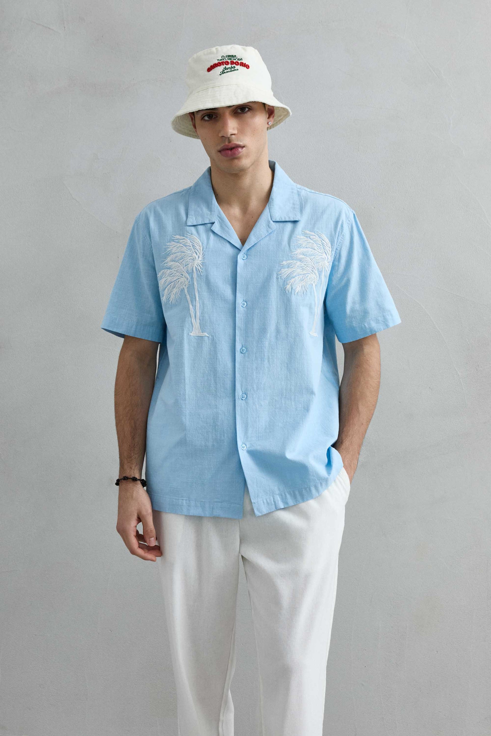 Camisa de manga corta celeste de Imperio con cuello cubano y bordado de palmeras blancas en el pecho, vista frontal.