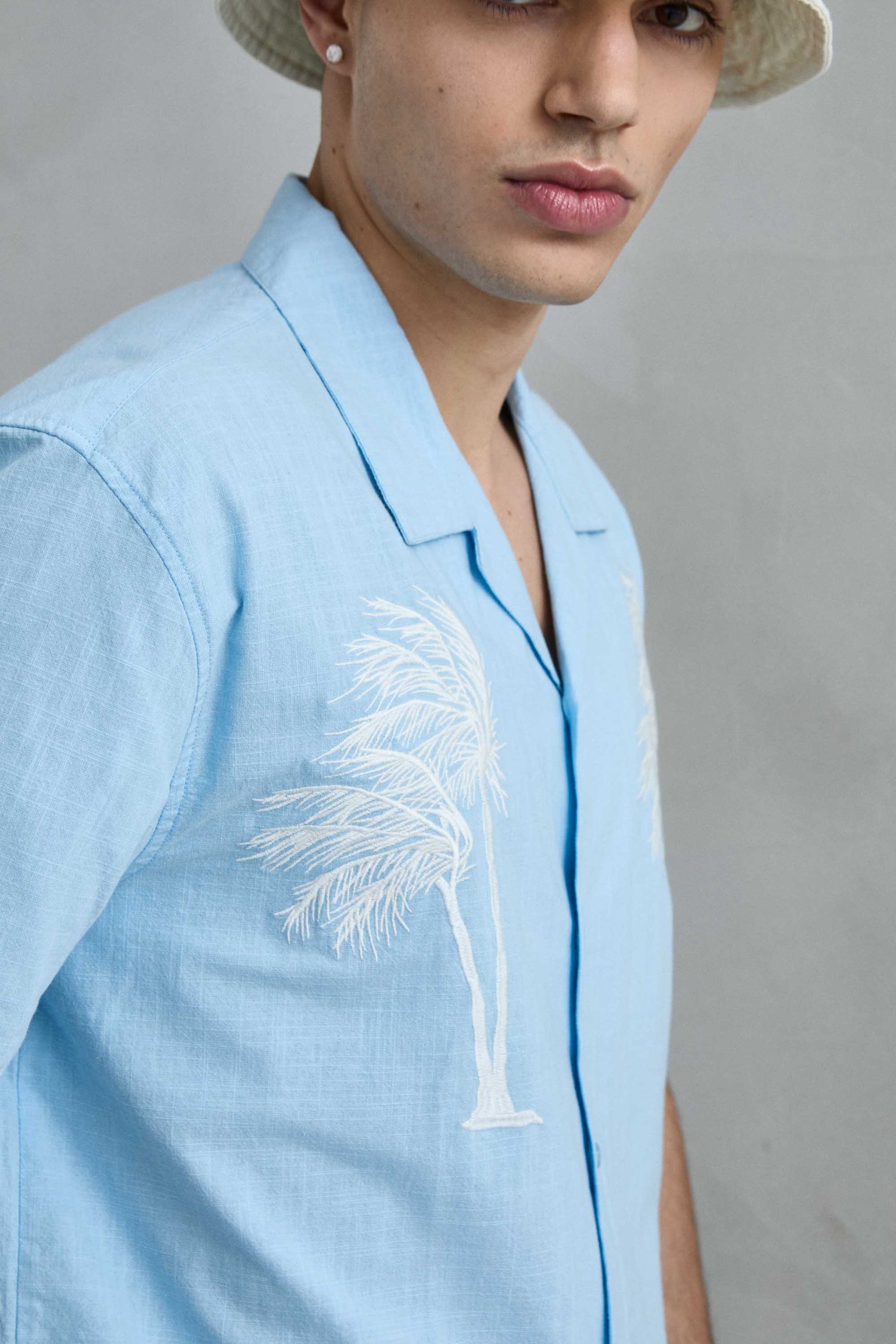 Modelo luciendo camisa de manga corta azul claro de Imperio con detalle de cuello cubano y ajuste relajado.
