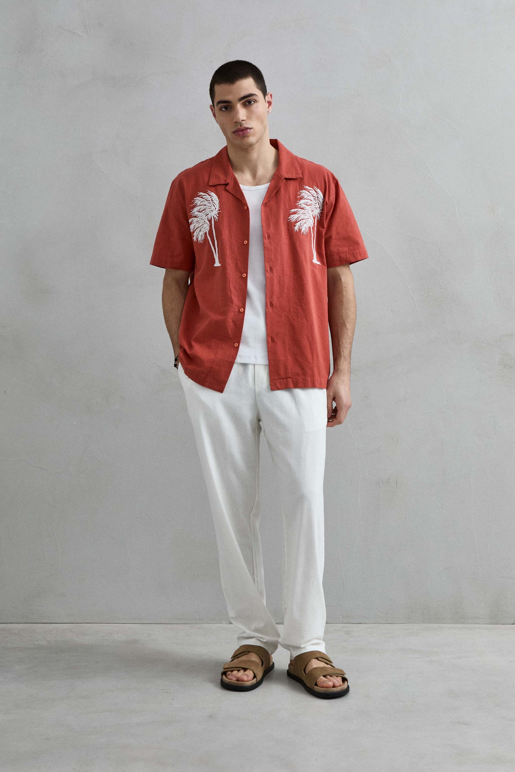 Conjunto de verano con camisa terracota de Imperio, cuello cubano y pantalones blancos de estilo sofisticado.