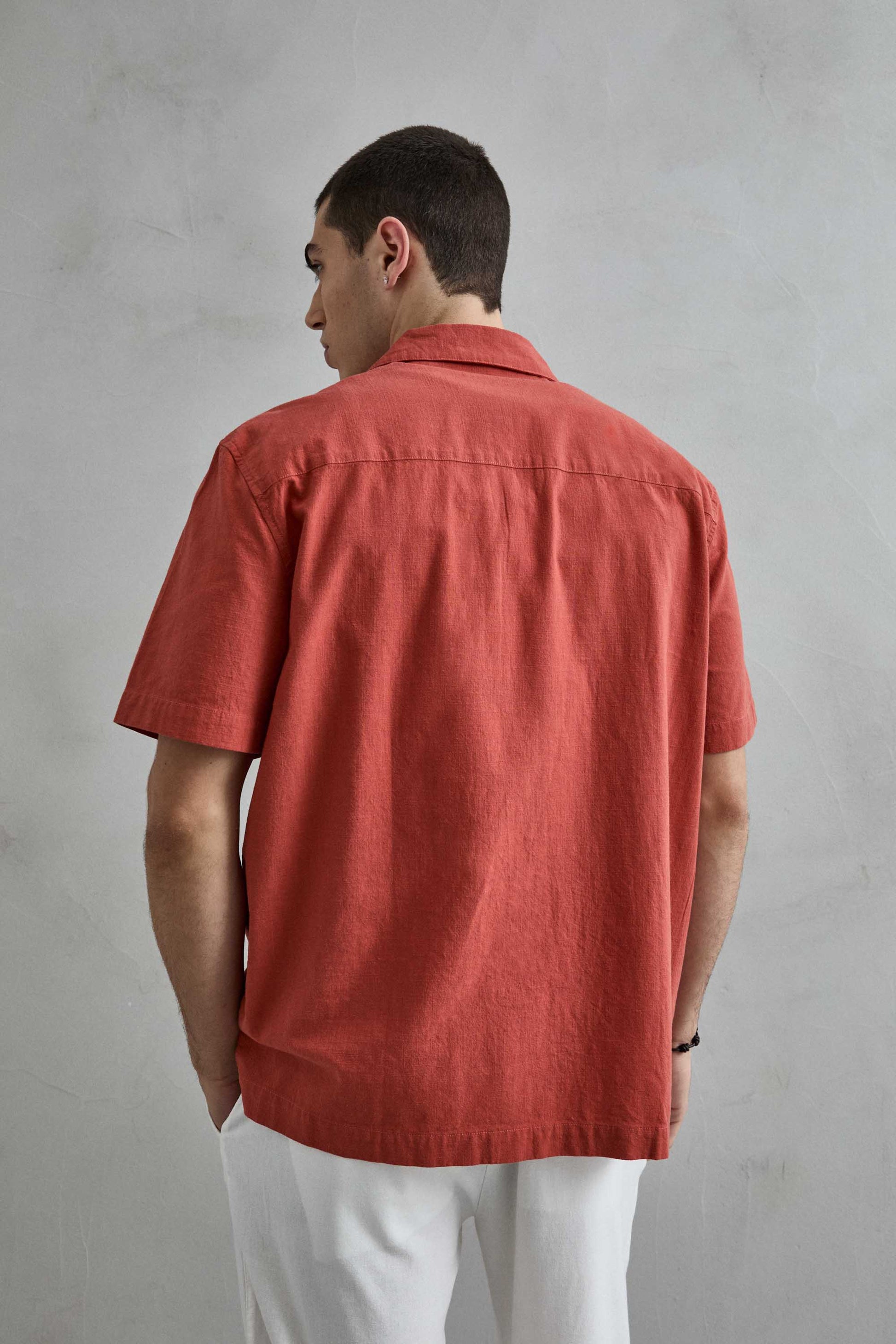 Modelo posando con camisa terracota de manga corta Imperio, destacando el diseño de cuello cubano y corte fluido.