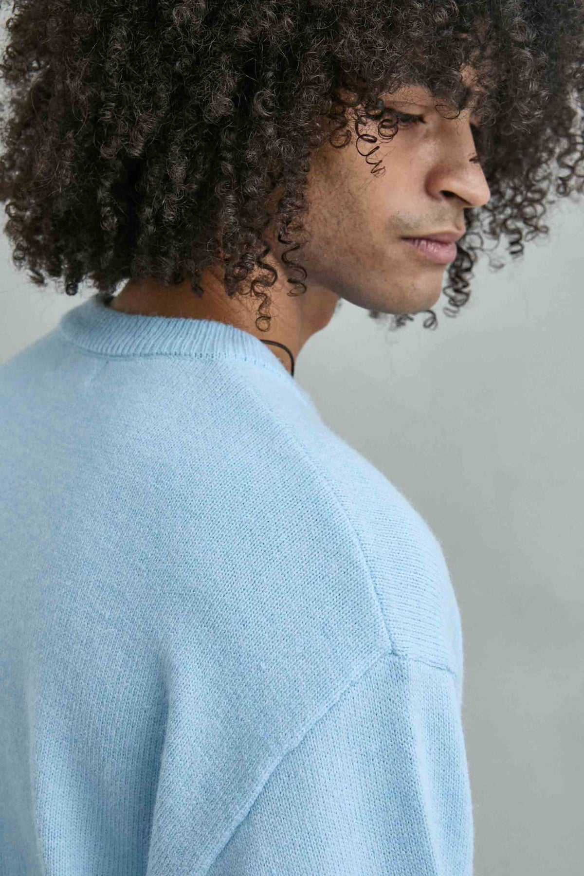 Detalle del tejido de punto y los acabados del jersey liso oversize de hombre en azul celeste