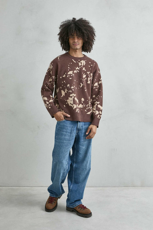 Vista de cuerpo entero del jersey oversize marrón y beis combinado con vaqueros azules