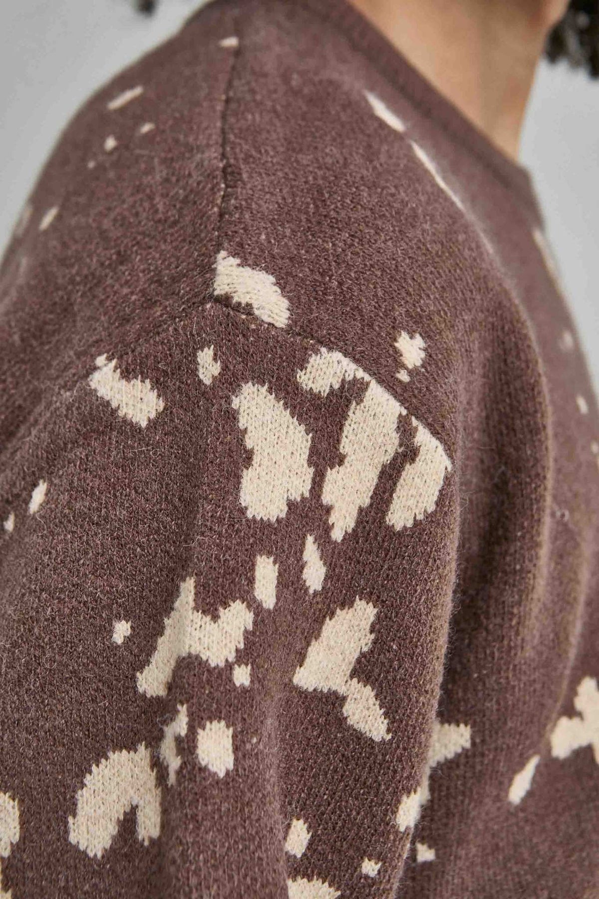 Detalle del punto, el hombro caído y los motivos beis del jersey oversize marrón