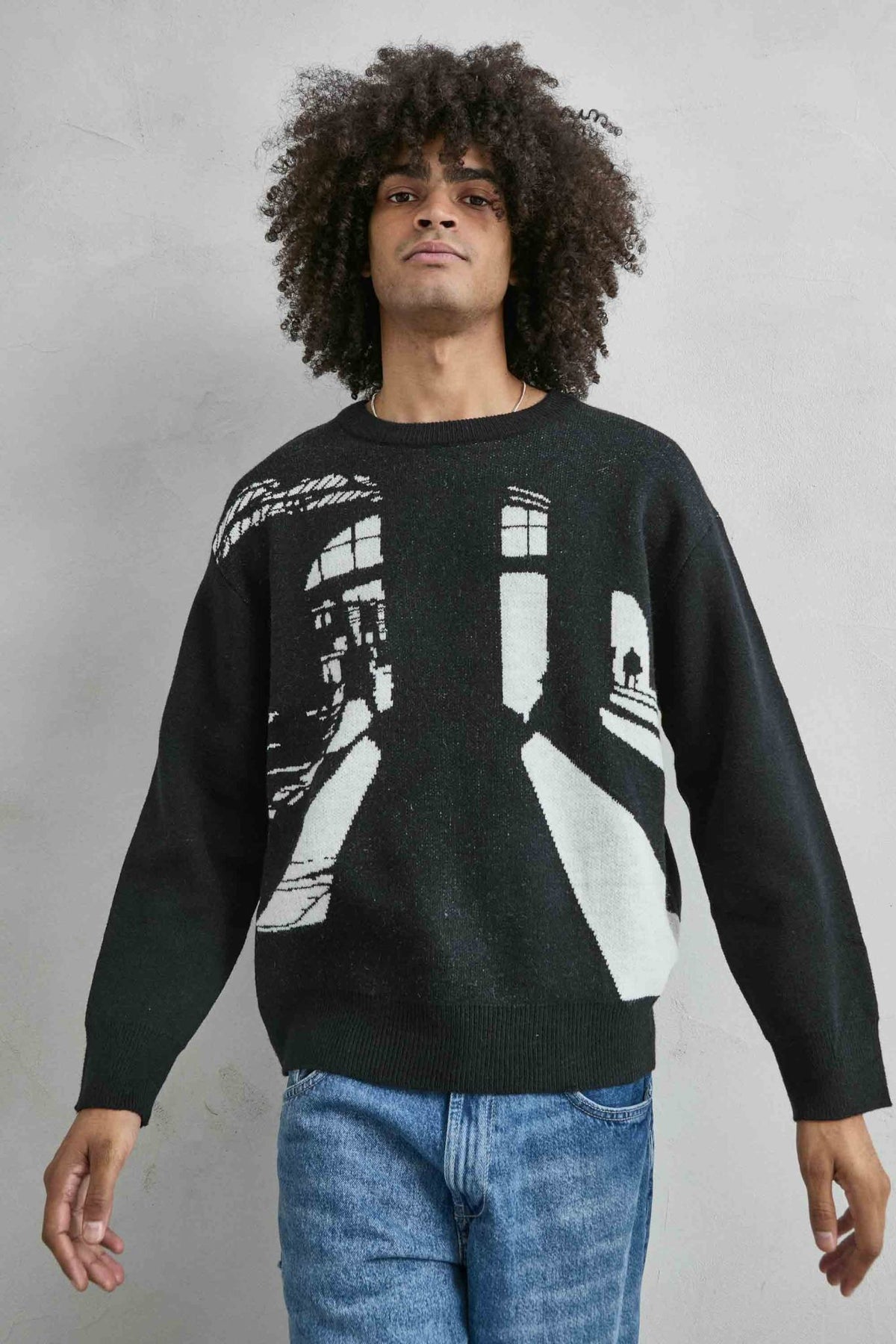 Vista frontal de medio cuerpo del jersey oversize negro con dibujo arquitectónico en blanco