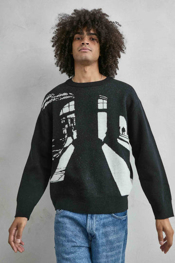 Vista frontal de medio cuerpo del jersey oversize negro con dibujo arquitectónico en blanco