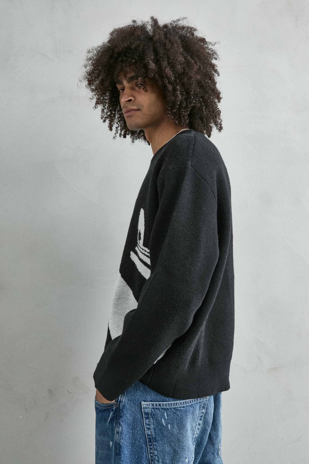 Vista lateral del jersey oversize negro con dibujo arquitectónico en blanco