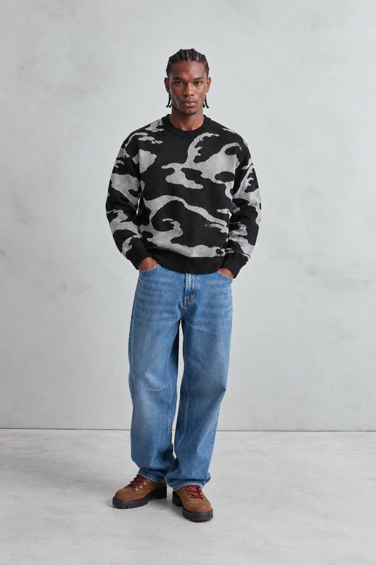 Vista de cuerpo entero del jersey oversize negro y gris combinado con vaqueros azules