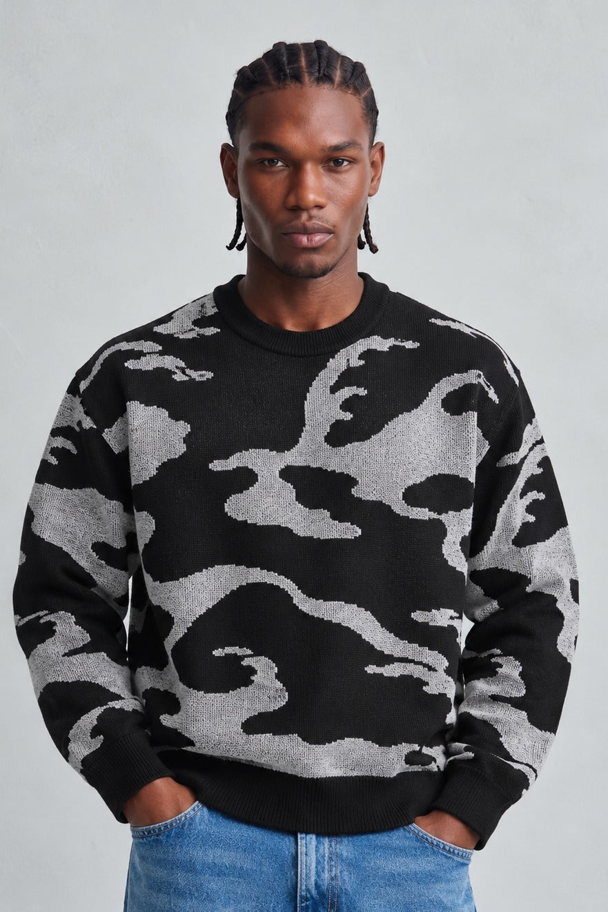 Vista frontal de medio cuerpo del jersey oversize negro y gris con dibujo abstracto y cuello redondo
