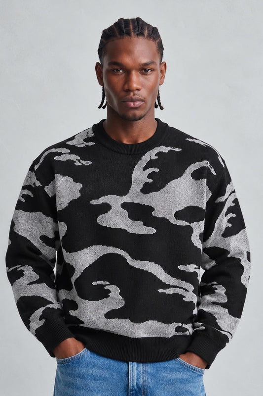 Vista frontal de medio cuerpo del jersey oversize negro y gris con dibujo abstracto y cuello redondo