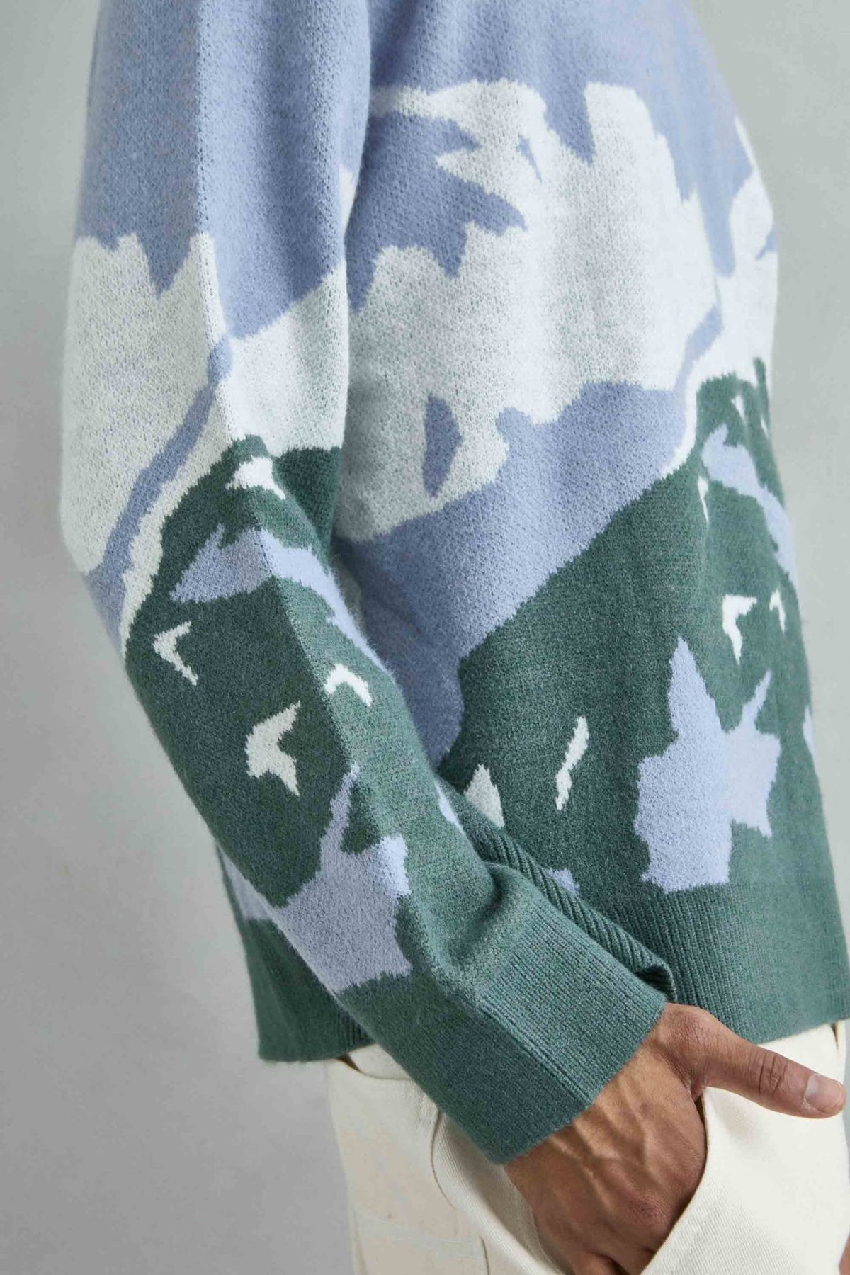 Detalle del tejido del jersey oversize con dibujo abstracto de ondas en azul lila, verde y blanco