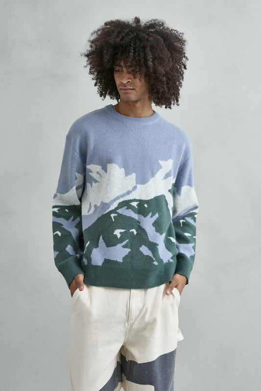 Vista frontal de medio cuerpo del jersey oversize con dibujo abstracto de ondas en azul lila, verde y blanco