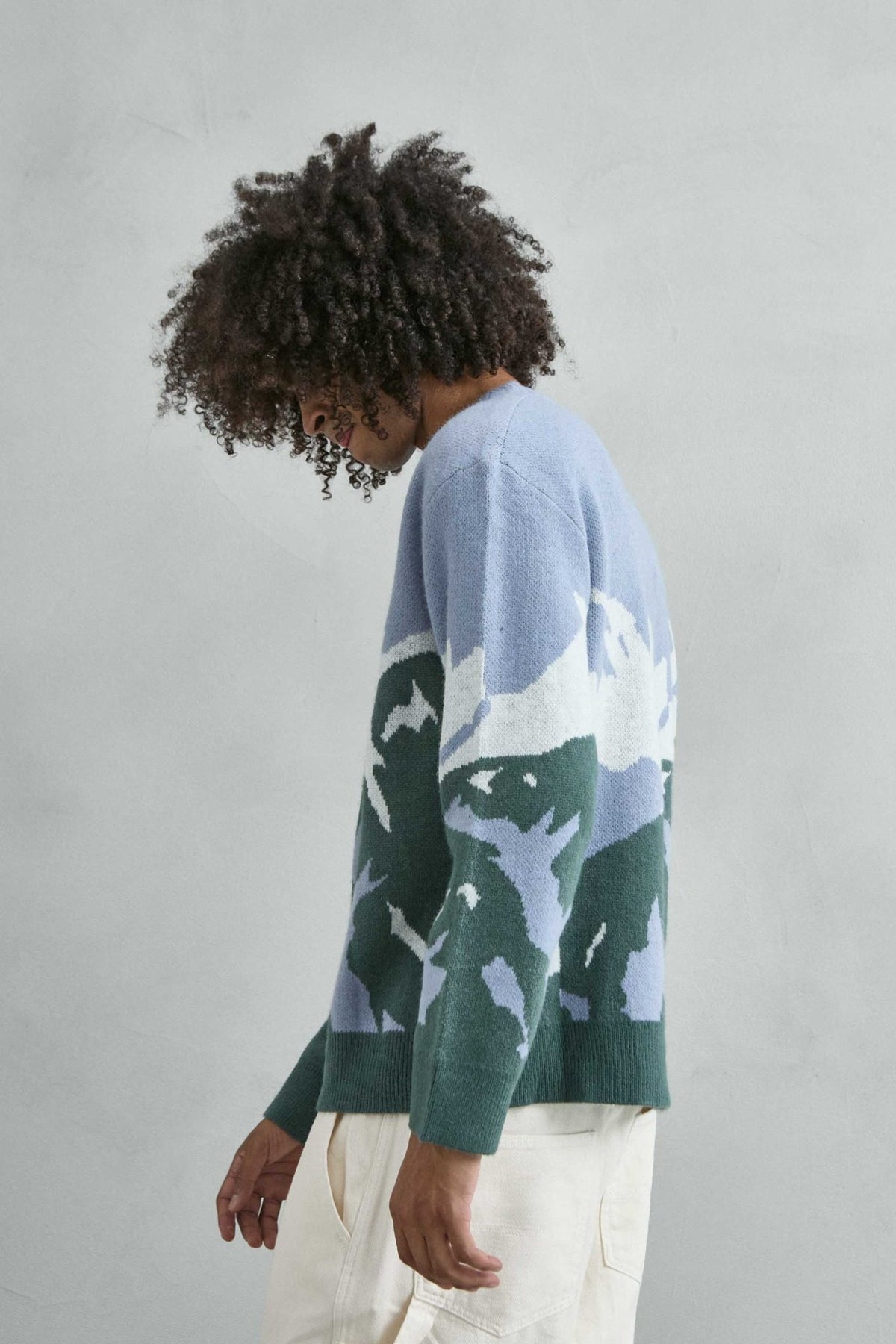Vista lateral del jersey oversize con dibujo abstracto de ondas en azul lila, verde y blanco