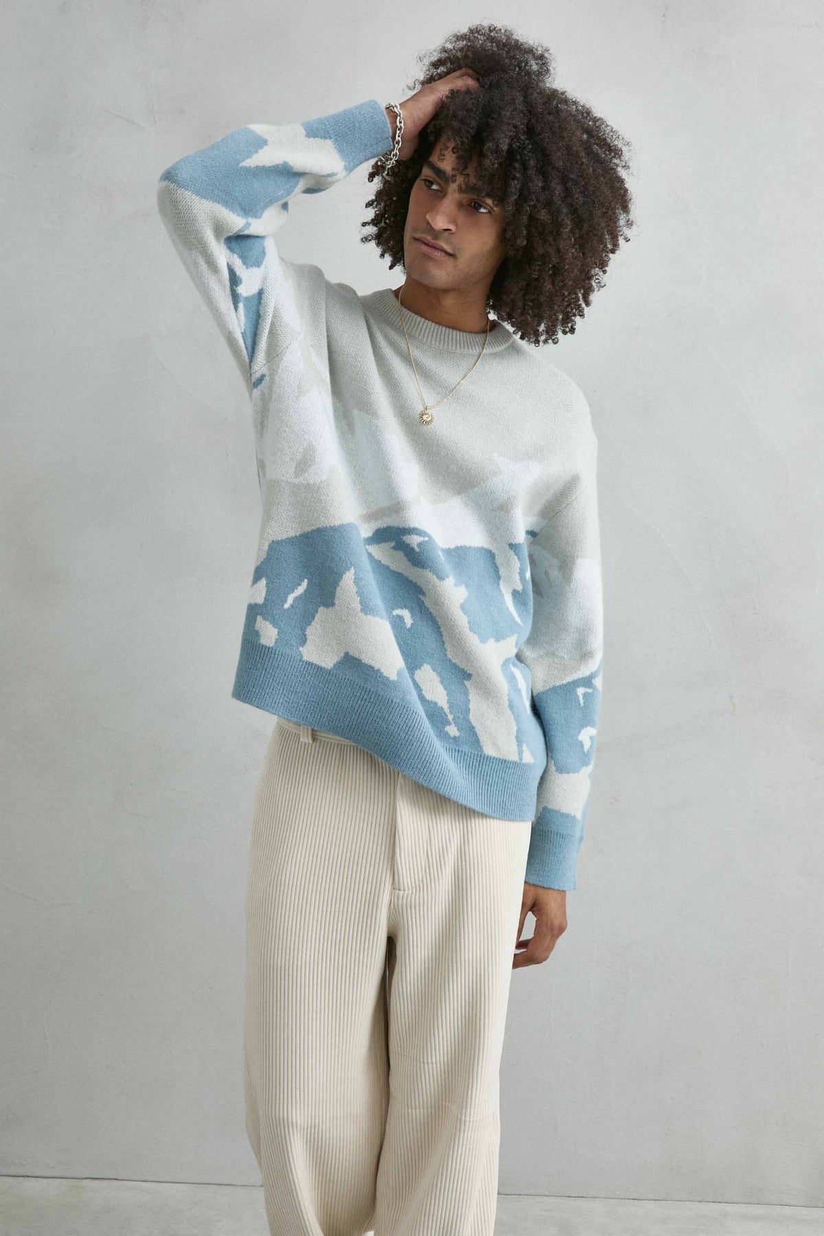 Vista frontal de medio cuerpo del jersey oversize con dibujo abstracto de ondas en gris claro, azul y blanco