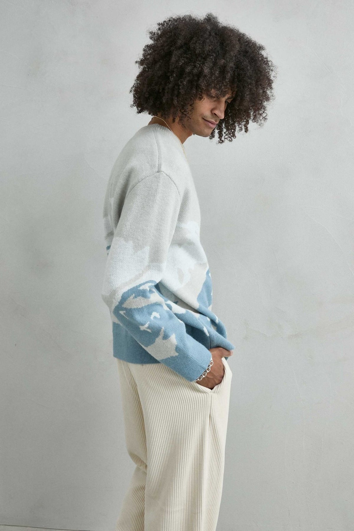 Vista lateral del jersey oversize con dibujo abstracto de ondas en gris claro, azul y blanco