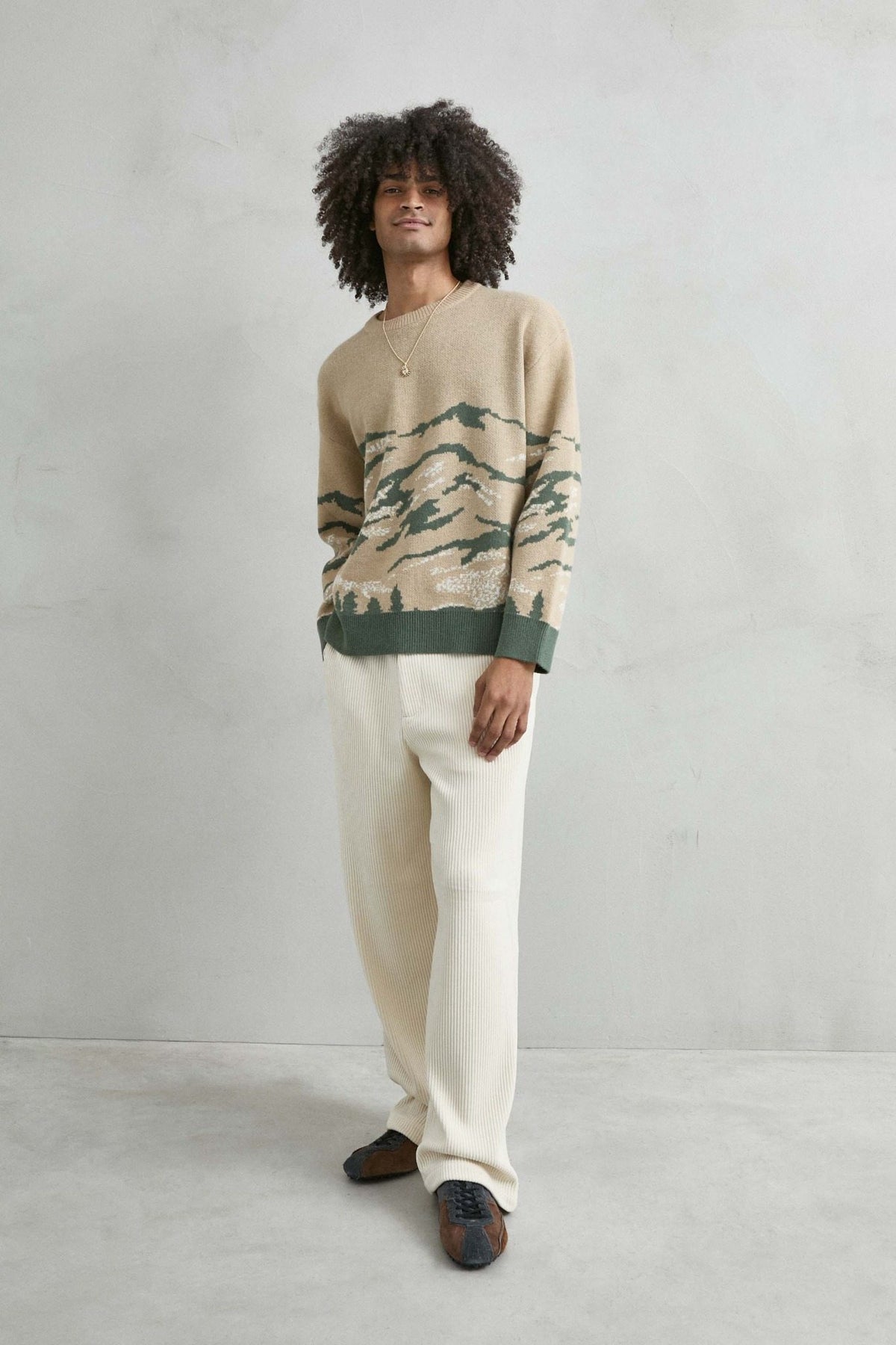 Vista de cuerpo entero del jersey oversize con paisaje de montañas en arena y verde