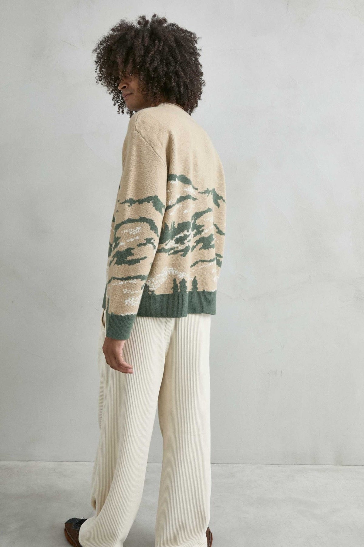 Vista trasera del jersey oversize con paisaje de montañas en arena y verde
