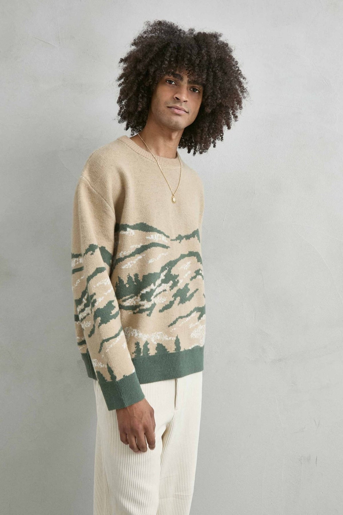 Vista frontal de medio cuerpo del jersey oversize con paisaje de montañas en arena y verde