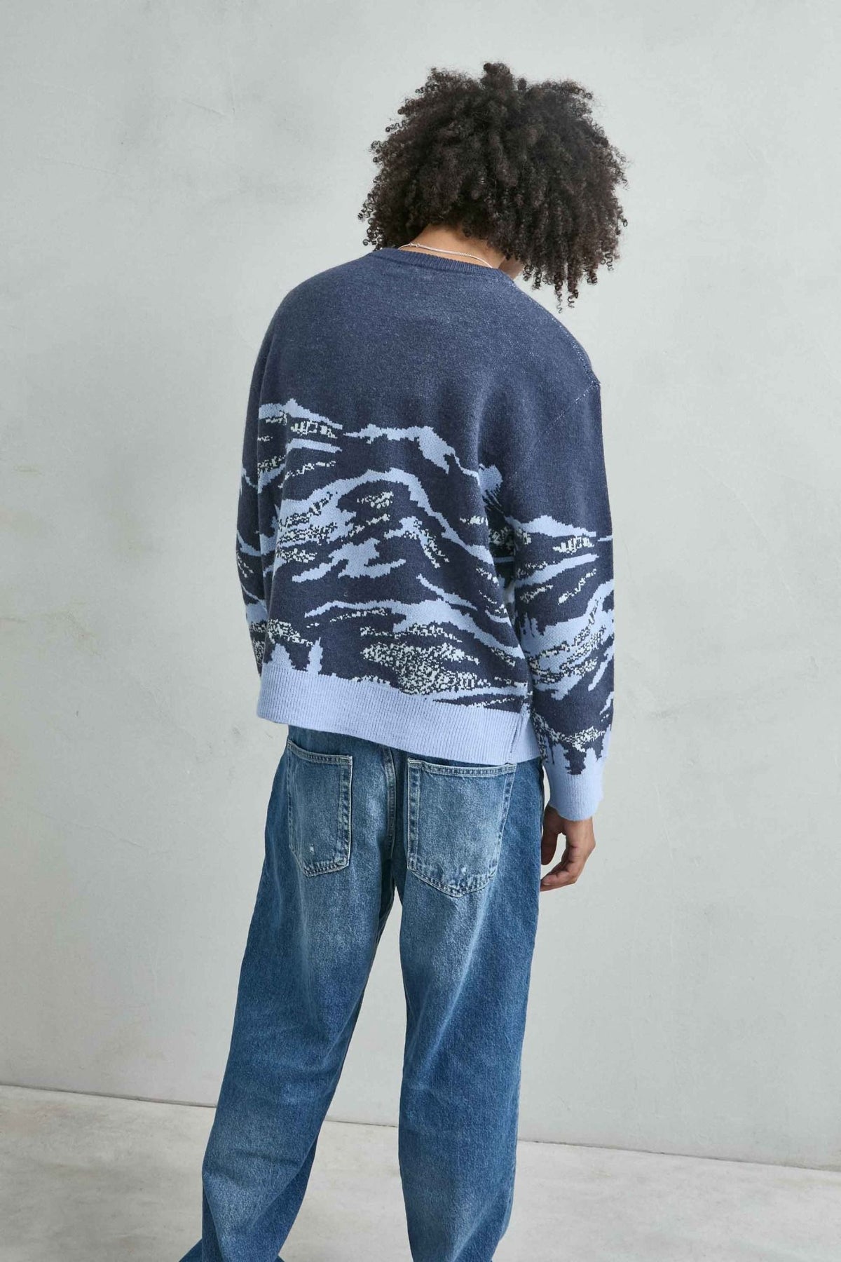 Vista trasera del jersey oversize con paisaje de montañas en azul marino y celeste