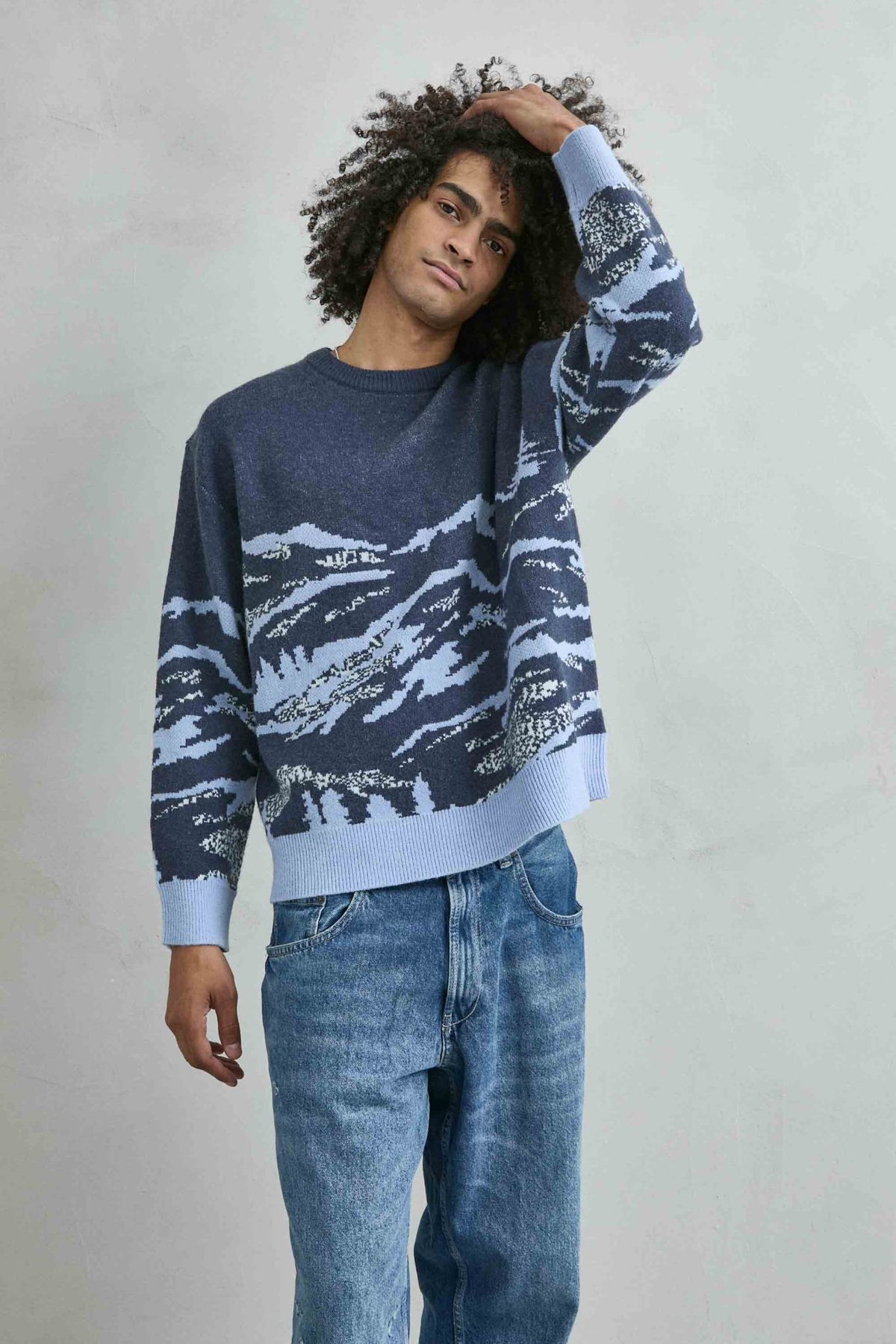 Vista frontal de medio cuerpo del jersey oversize con paisaje de montañas en azul marino y celeste