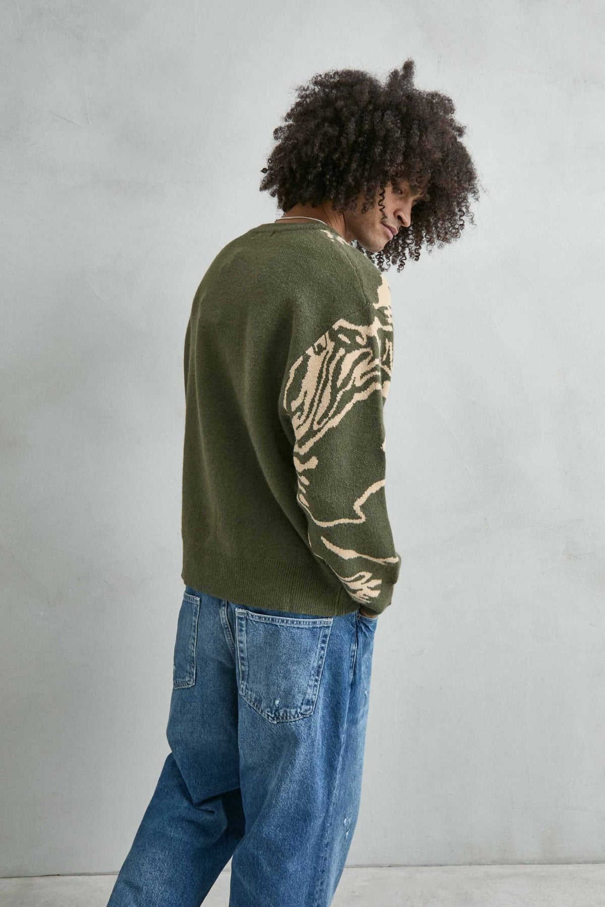 Vista trasera del jersey oversize verde oliva con dibujo abstracto en beis