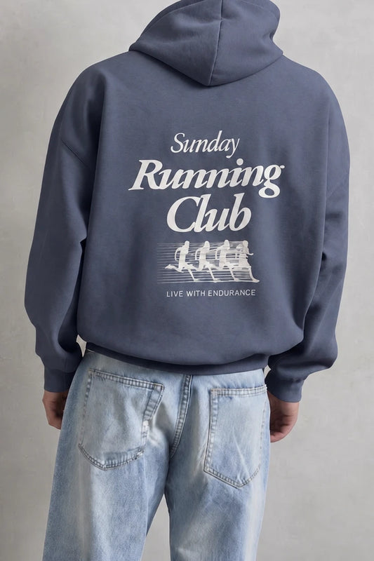 Espalda de sudadera azul con texto Sunday Running Club y siluetas blancas de corredores
