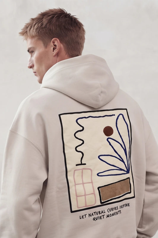 Espalda de sudadera beige con composición rectangular de hojas azules, líneas y formas geométricas