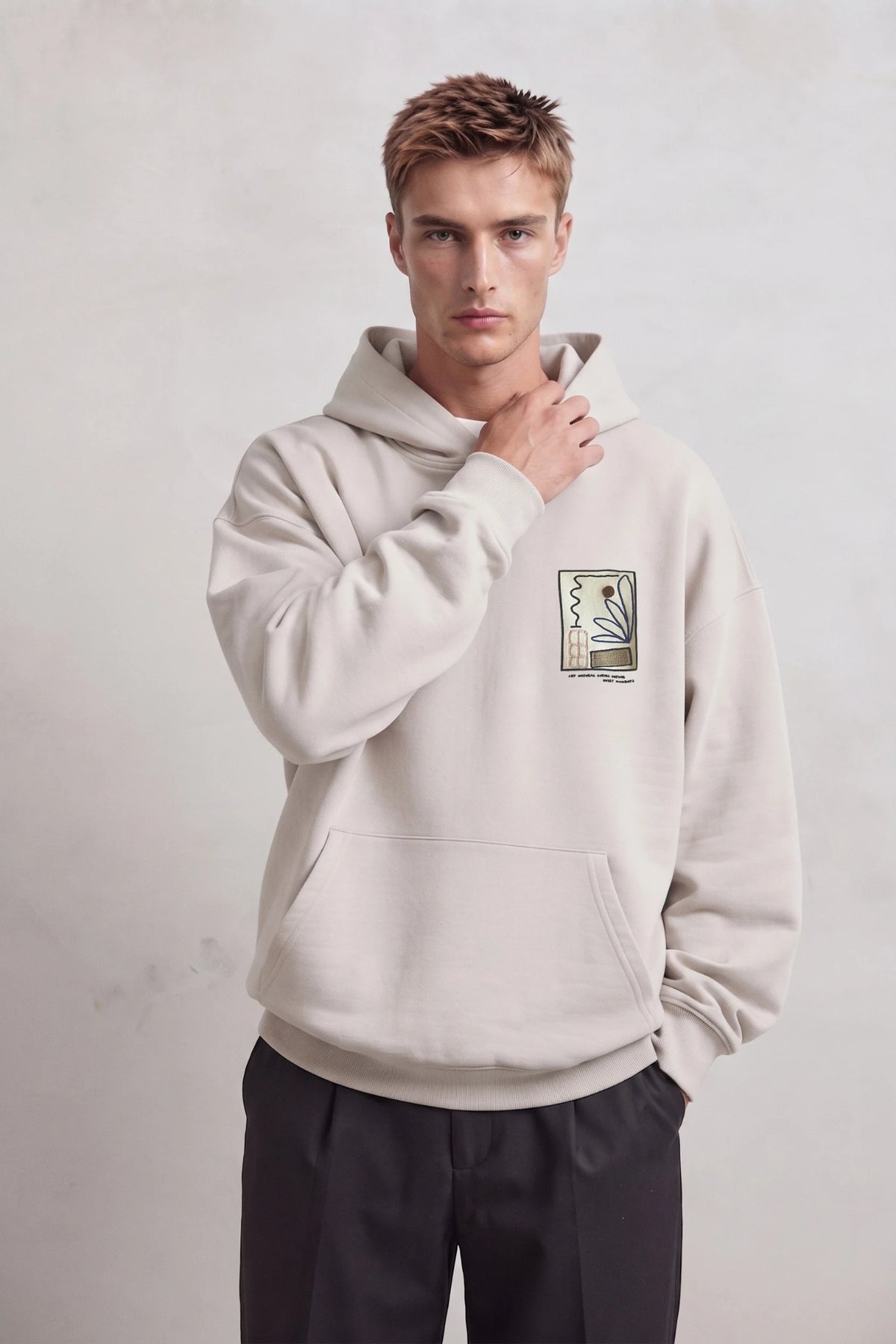 Sudadera beige oversize de hombre con capucha y pequeño gráfico botánico abstracto en el pecho