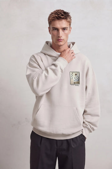 Sudadera beige oversize de hombre con capucha y pequeño gráfico botánico abstracto en el pecho
