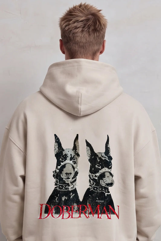 Espalda de sudadera beige con dos perros dóberman en negro y gris y grandes letras rojas Doberman