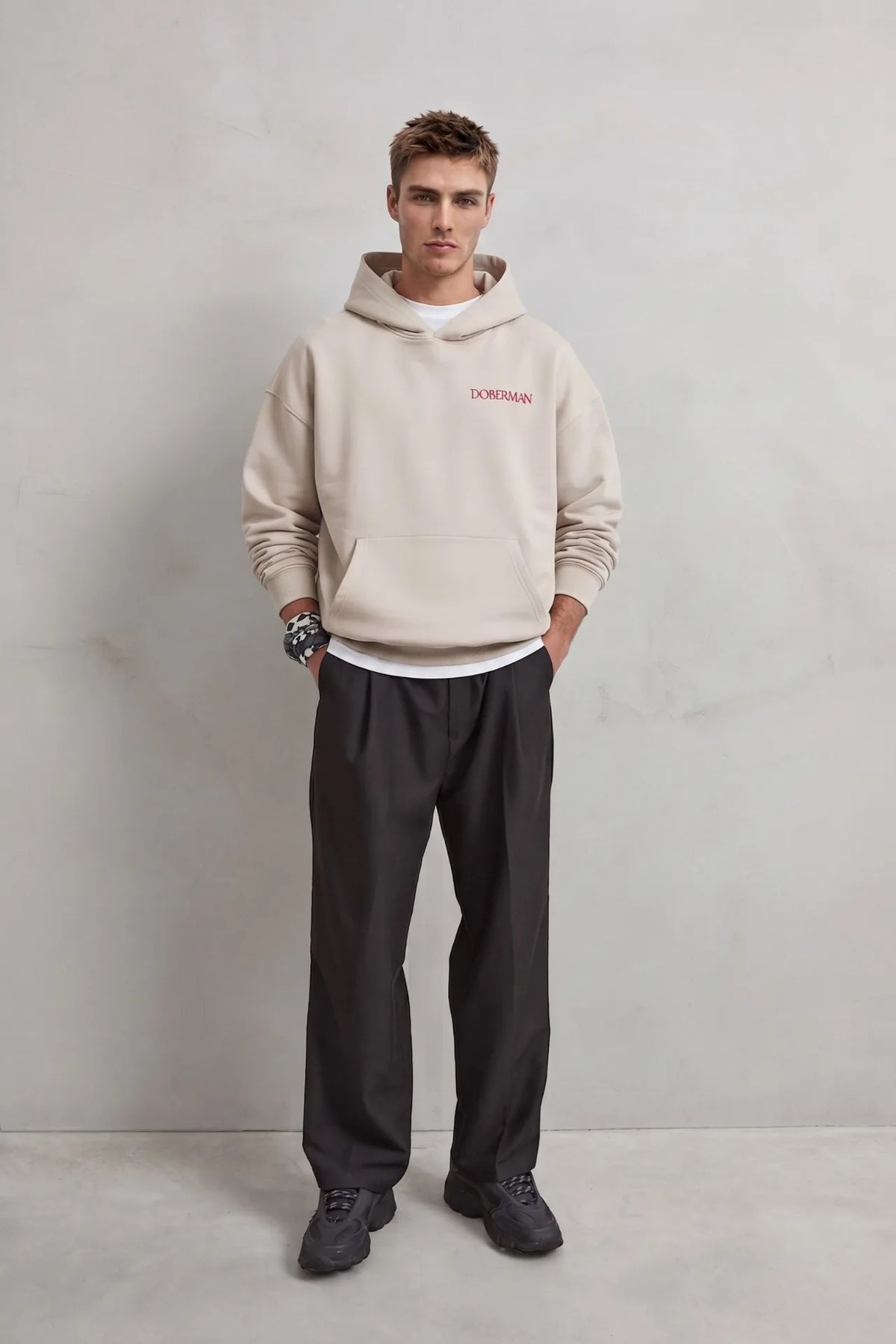 Vista frontal de cuerpo entero con sudadera beige Doberman y pantalones negros