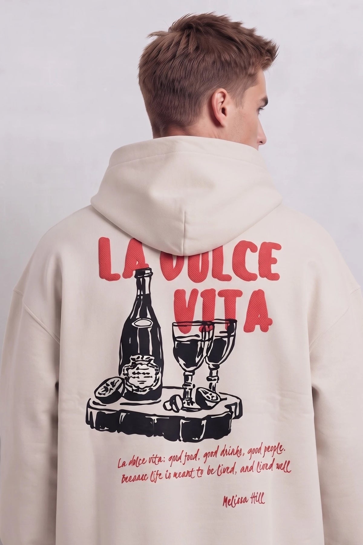 Espalda de sudadera beige con texto rojo La Dolce Vita y dibujo negro de botella y copas