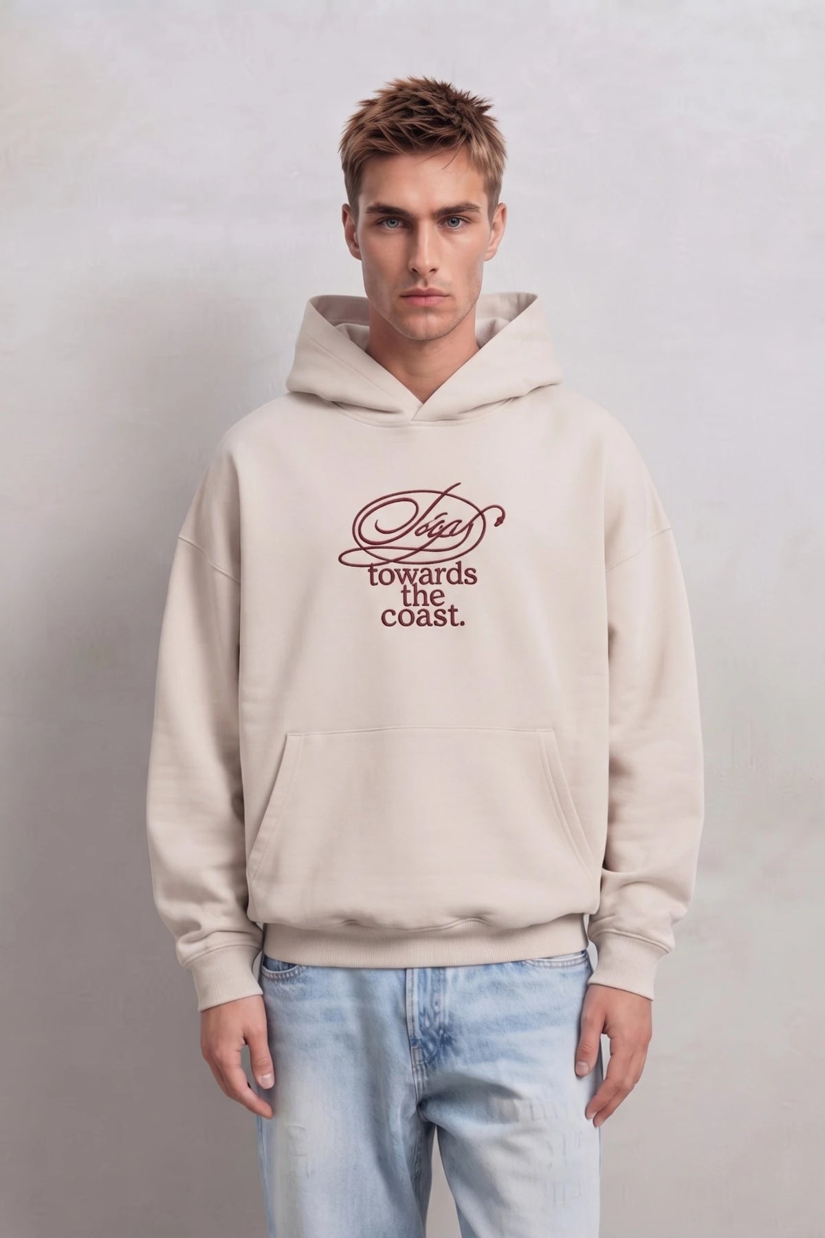 Sudadera beige oversize de hombre con capucha y texto burdeos en el pecho, vista frontal