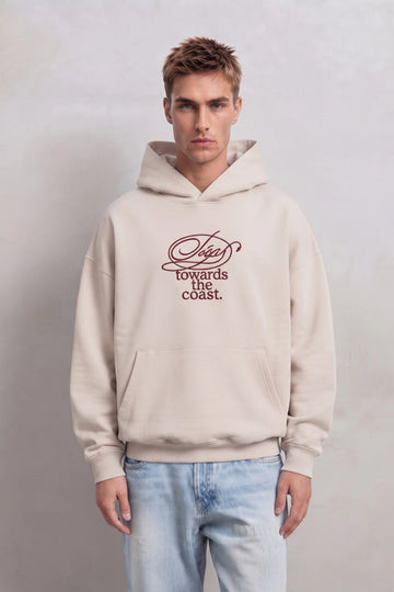 Sudadera beige oversize de hombre con capucha y texto burdeos en el pecho, vista frontal