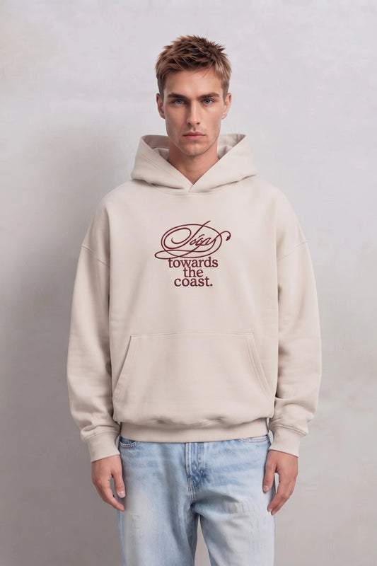 Sudadera beige oversize de hombre con capucha y texto burdeos en el pecho, vista frontal