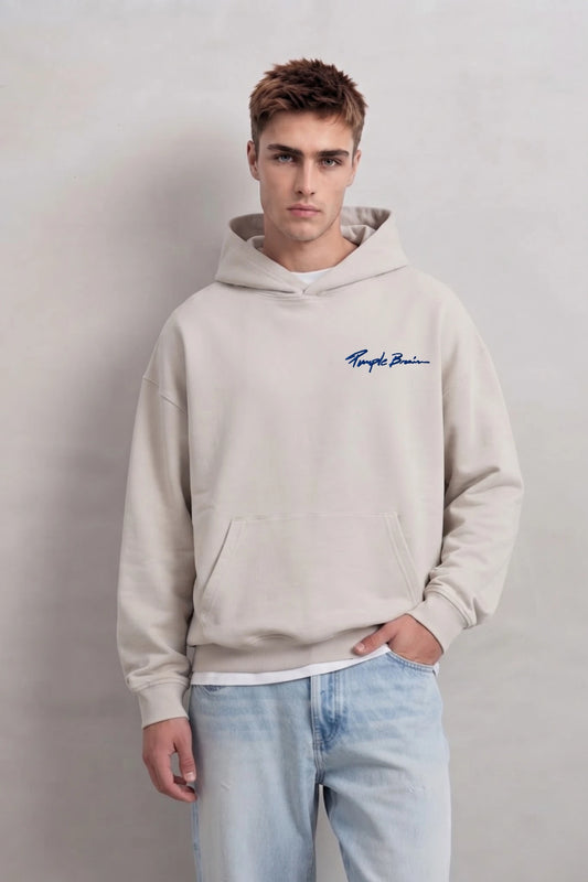 Sudadera beige oversize de hombre con capucha y pequeño texto azul en el pecho, vista frontal