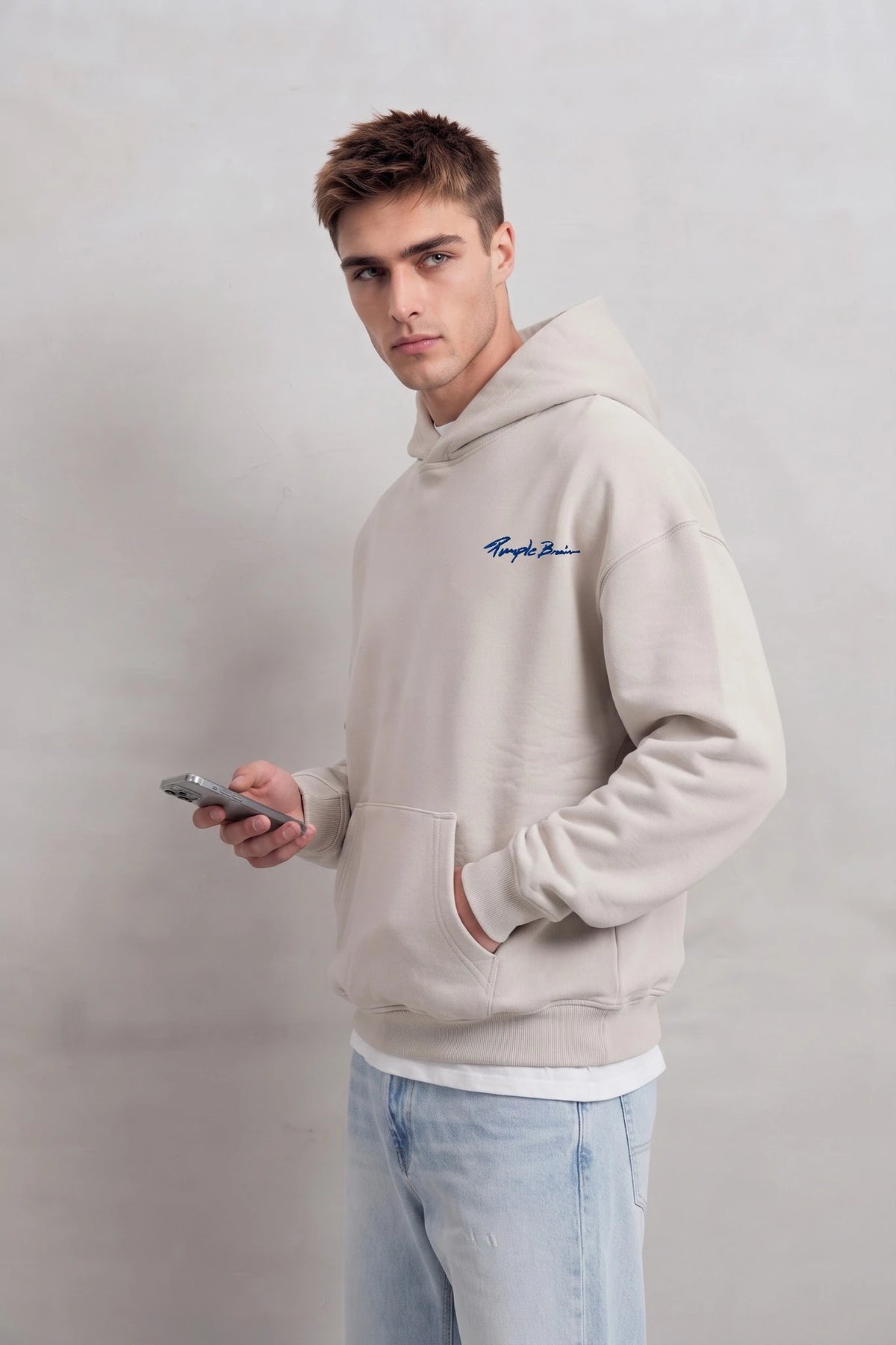 Vista lateral de sudadera beige oversize con capucha y bolsillo canguro